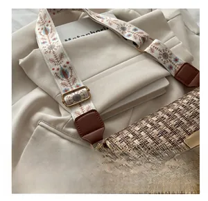 Close-up of vintage tweed bag with floral embroidered strap and gold buckle adjustment