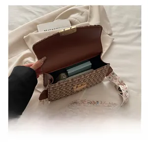 Detail view of woven plaid crossbody bag with wide shoulder strap and interior capacity