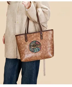 Detail of vintage brown tote featuring embossed elephant motif and cracked leather texture