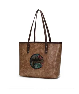 Detailed view of retro embossed elephant pattern on brown vintage leather tote bag