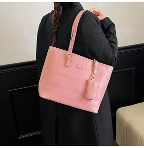 Détail du sac cabas rose avec motifs de cœurs gaufrés, boucles dorées et porte-cartes