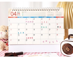 Detail of 2025 calendar April page with twin-wire binding and decorative handwritten text