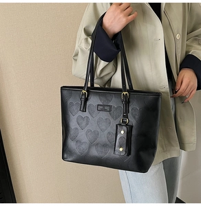 Détail du cabas noir gaufré de cœurs avec petite pochette et logo métallique