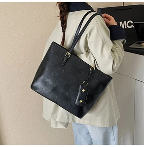 Détail du sac cabas noir avec motif cœur embossé et boucle de réglage dorée élégante