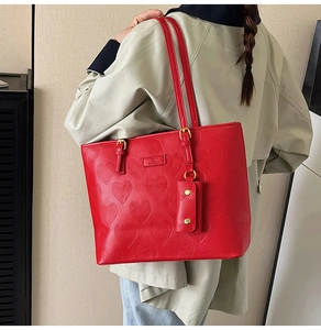 Gros plan du grand sac cabas rouge avec cuir gaufré de cœurs et mini pochette