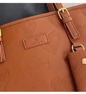 Détail du sac cabas en cuir marron avec gaufrage en cœur et ferrures métalliques dorées