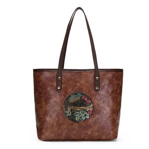 Brown vintage leather tote bag with ethnic floral embossed medallion and gold studs