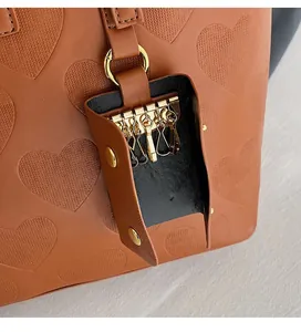 Détail du sac cabas en cuir marron avec gaufrage en cœur et une pochette à clés externe
