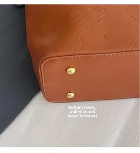 Détails du fond du sac en cuir marron gaufré avec rivets de protection dorés