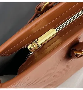 Gros plan d'une fermeture éclair dorée et du cuir marron texturé d'un grand sac