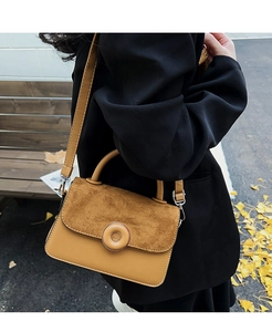 Detail of a vintage mustard handbag with matte suede flap and round metallic buckle