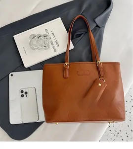 Détail du sac cabas marron à gaufrage cœur avec tablette et livres comme référence de taille