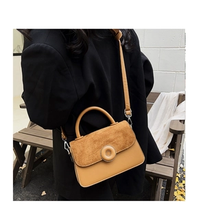Close-up of caramel leather crossbody bag with suede patchwork and round metal lock buckle
