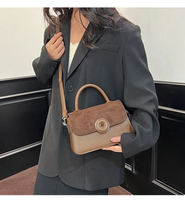 Detail of a brown two-tone crossbody bag featuring a frosted flap and silver round buckle
