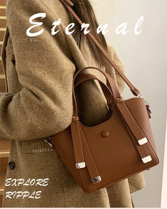 Detailed texture of brown litchi grain leather bucket bag with silver metal accents