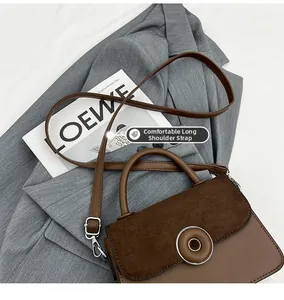 Close-up of brown suede and leather patchwork handbag with gold metal clasp detail