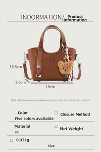 Detail view of brown tote with bear pendant and red scarf showing 18x8.5x16.5cm dimensions