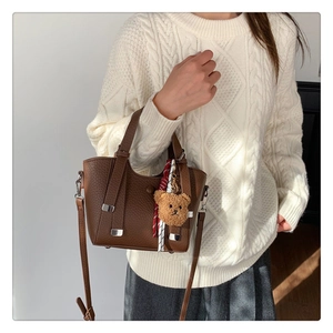 Detailed view of brown lychee grain leather bucket bag with teddy bear charm and scarf