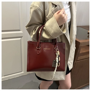 Détail d'un sac cabas bordeaux brillant avec lettrage et pendentif chocolat créatif