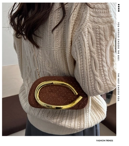 Detail of velvet evening clutch with gold streamlined handle and rivet accents