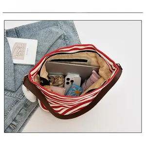 Spacious red striped canvas tote interior with laptop, phones, and leather strap