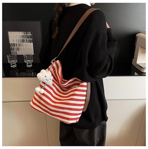 Détail du sac en toile rayé rouge avec bandoulière en cuir et charm nuage blanc