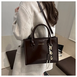 Détail du cabas en cuir brillant marron foncé avec bandoulière chaîne et imprimé mode