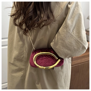 Detail of burgundy velvet clutch with sparkling rhinestones and gold ring handle