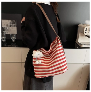 Détail du sac en toile rayé rouge et blanc avec bandoulière en cuir et charm nuage