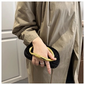 Detail showing elegant gold metal handle and sparkling velvet evening clutch bag in hand