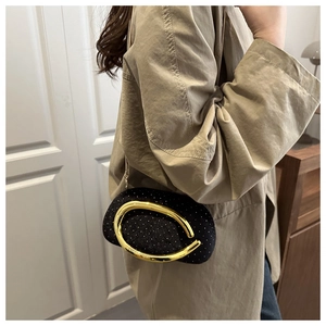 Detailed view of luxury black velvet clutch with sparkling crystals and gold metal ring