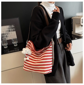 Détail du sac cabas en toile rayé rouge et blanc avec bandoulière en cuir et breloque