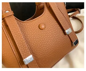Close-up of brown litchi pattern leather texture with silver hardware and fine stitching