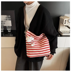 Détail du sac cabas en toile rayé rouge et blanc avec pendentif nuage en peluche sur modèle