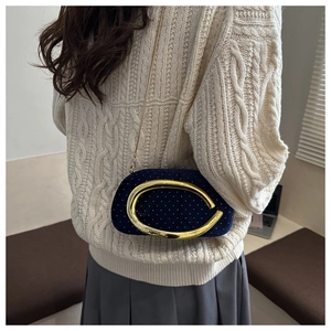 Detail of dark blue velvet clutch with gold C-ring buckle and fine chain strap