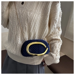 Close-up of blue velvet round bag featuring gold C-buckle and white polka dot accents
