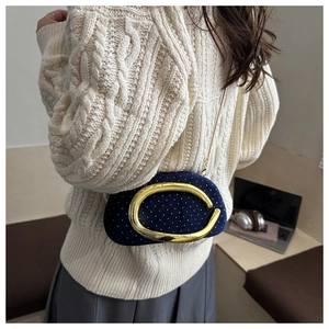 Detail of dark blue velvet evening bag with sparkling rhinestones and golden C-ring buckle
