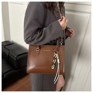 Détail d'un sac cabas en cuir marron brillant avec texte imprimé Fashion & Bags et chaîne