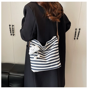 Détail du sac cabas en toile rayée bleue avec bandoulière en cuir et charm nuage