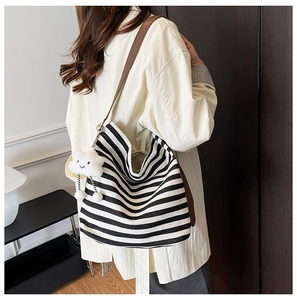Détail du sac hobo en toile rayée avec bandoulière en cuir et charm nuage peluche