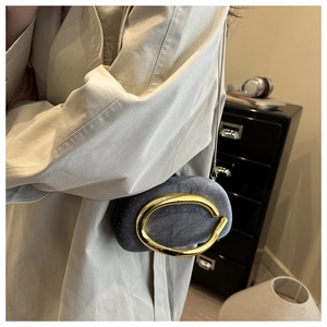 Close-up of grey velvet clutch bag with sparkling rhinestones and a large gold metal ring