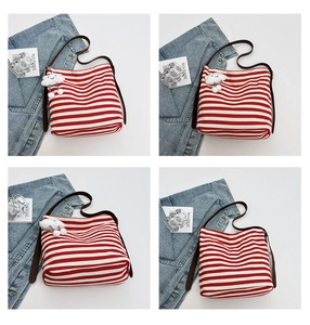 Detail view of red striped canvas tote bag featuring brown leather strap and cloud charm