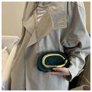Detail of dark green velvet evening clutch with gold studs and large metal handle