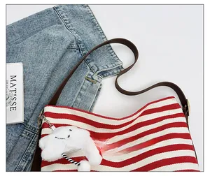 Detail showing adjustable brown leather strap on red and white striped canvas tote bag
