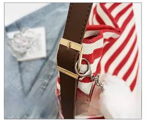 Detail of red striped canvas bag with brown leather strap and gold hardware accents