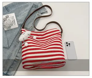 Detail of red striped canvas tote bag with leather straps and cloud charm accessory