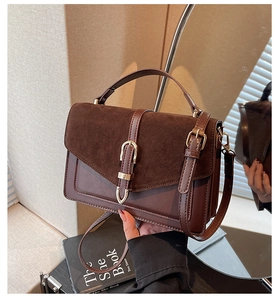 Detail of vintage brown crossbody bag featuring dual-textured leather and gold metal buckle