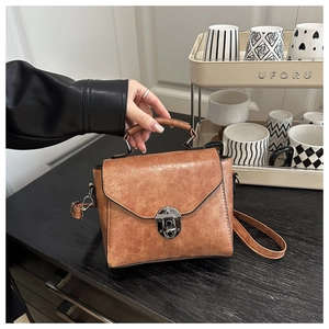 Détail du sac bandoulière marron vintage avec rabat triangulaire et fermoir argenté