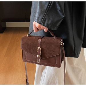 Detail of chocolate brown suede flap and golden buckle on retro crossbody handbag