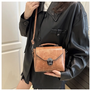 Détail d'un sac bandoulière marron vintage avec boucle en métal et poignée supérieure
